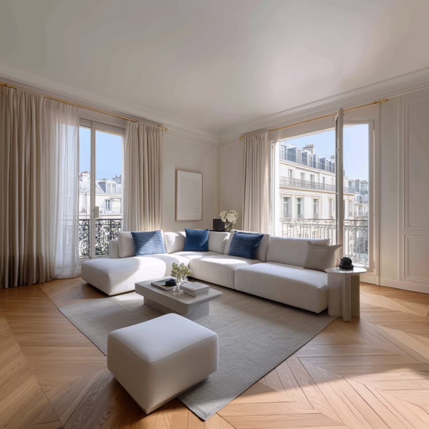 Salon d'appartement parisien élégant avec canapé beige et cadres muraux